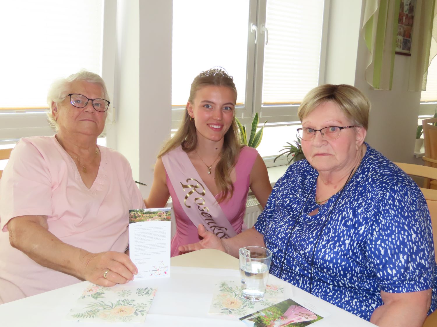 die Rosenkönigin neben zwei Bewohnerinnen